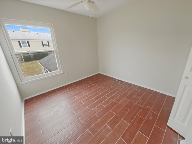 empty room featuring dark wood finished floors, baseboards, and ceiling fan