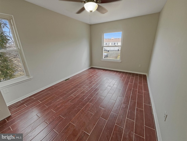 unfurnished room featuring dark wood finished floors, visible vents, baseboards, and ceiling fan