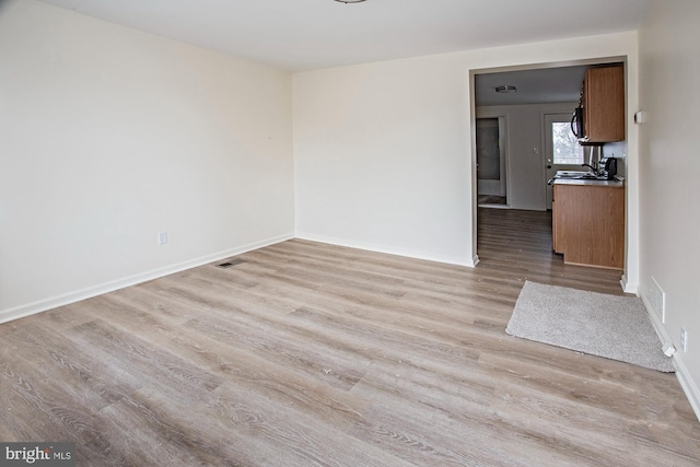 interior space with light wood-type flooring, baseboards, and visible vents