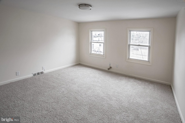 spare room with carpet flooring, baseboards, and visible vents