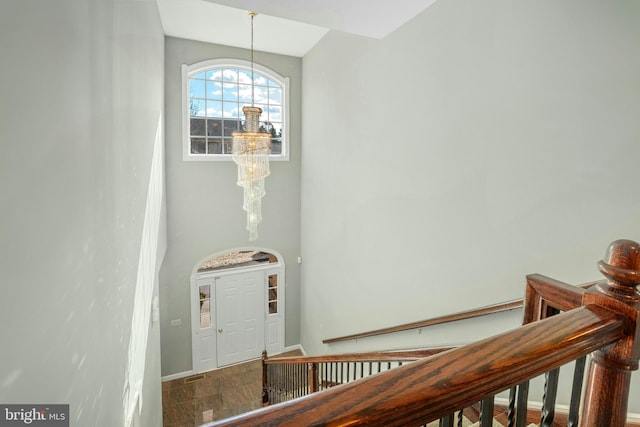 stairs featuring baseboards, an inviting chandelier, and wood finished floors