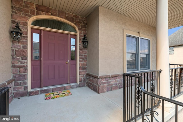 view of exterior entry featuring stucco siding and brick siding