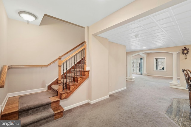 stairway with arched walkways, carpet floors, baseboards, and decorative columns