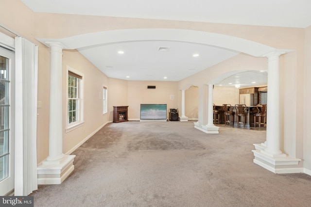 unfurnished living room featuring recessed lighting, a dry bar, ornate columns, and carpet floors