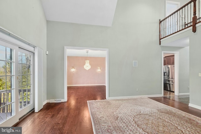 foyer featuring baseboards, a high ceiling, wood finished floors, and plenty of natural light