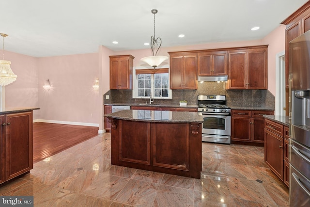 kitchen with stainless steel gas stove, built in refrigerator, under cabinet range hood, a sink, and tasteful backsplash