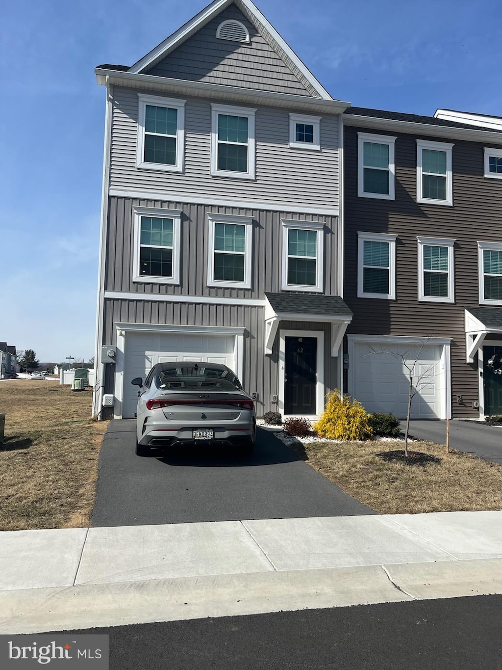 townhome / multi-family property featuring aphalt driveway, an attached garage, and board and batten siding