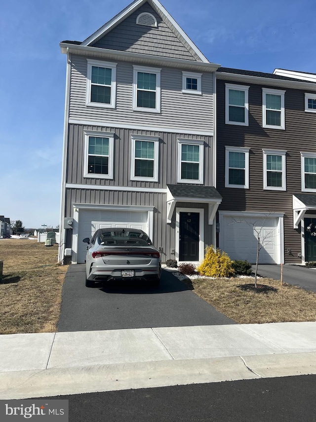 townhome / multi-family property featuring aphalt driveway, an attached garage, and board and batten siding