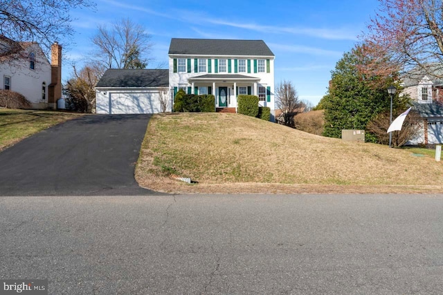 colonial house featuring aphalt driveway, a front yard, and an attached garage