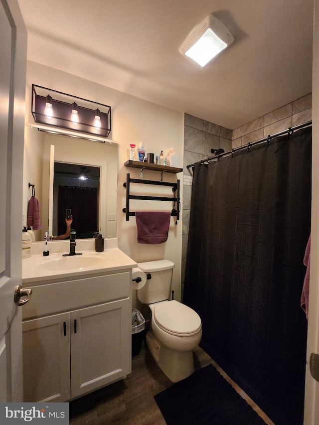 full bathroom with curtained shower, toilet, vanity, and wood finished floors