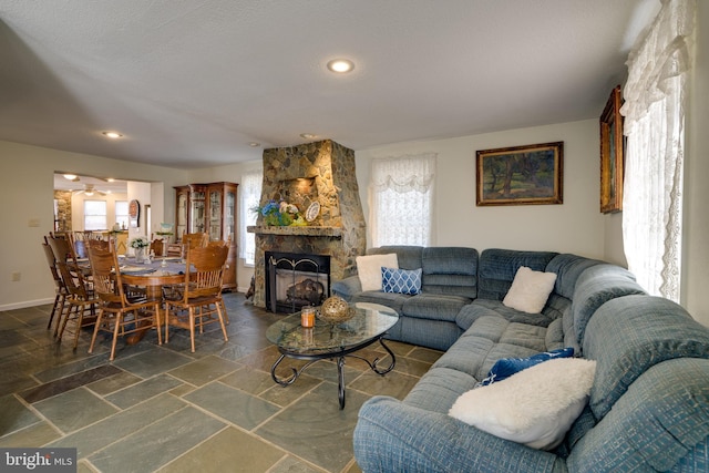 living room with stone tile floors, a stone fireplace, recessed lighting, and baseboards