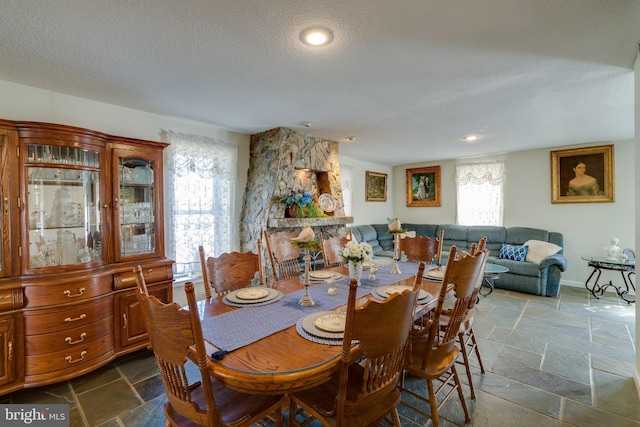 dining room with a wealth of natural light, a textured ceiling, and stone tile floors