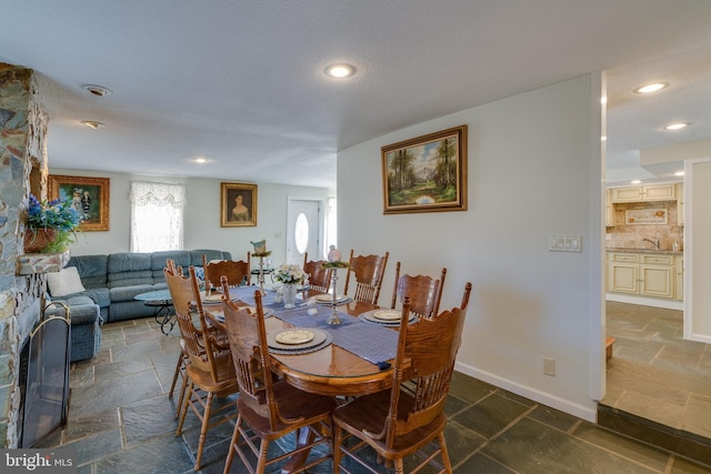 dining space featuring stone tile flooring, recessed lighting, and baseboards