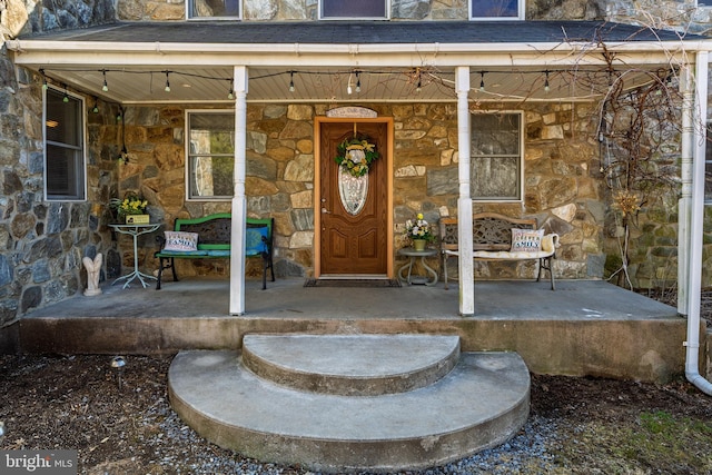 view of exterior entry with a porch and stone siding