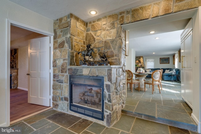 living room with a stone fireplace, stone tile floors, recessed lighting, and baseboards