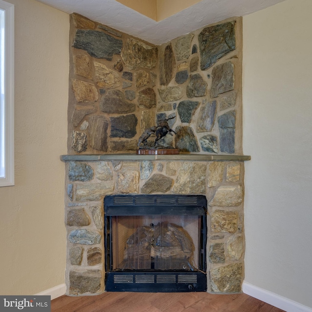 details with a stone fireplace, baseboards, and wood finished floors