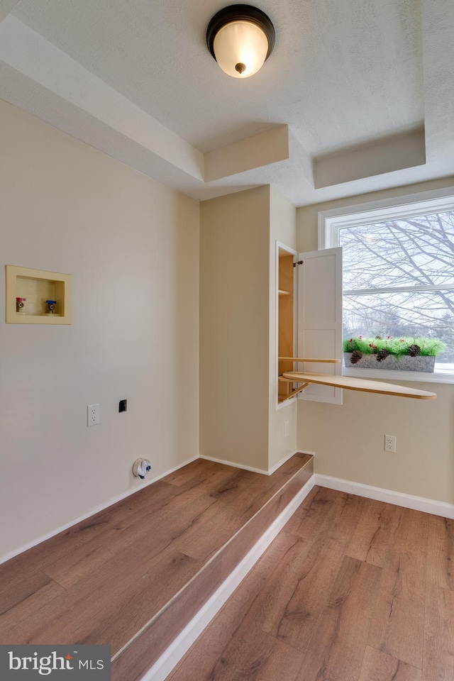 clothes washing area featuring wood finished floors, baseboards, hookup for an electric dryer, hookup for a washing machine, and laundry area