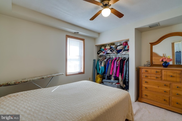 bedroom with a closet, light colored carpet, visible vents, and a ceiling fan