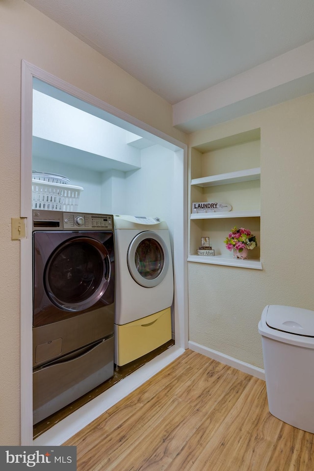 laundry area with built in shelves, wood finished floors, baseboards, laundry area, and washer and dryer