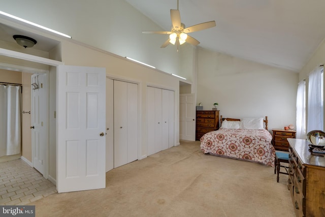 carpeted bedroom with high vaulted ceiling, multiple closets, and a ceiling fan