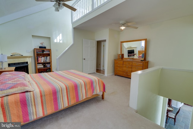 bedroom with a ceiling fan, carpet flooring, a fireplace, and a towering ceiling