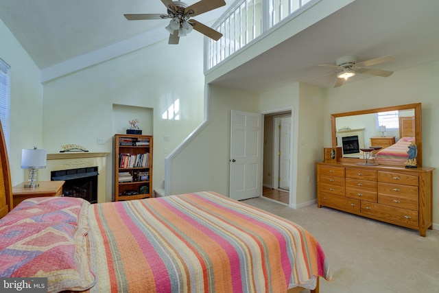 carpeted bedroom with a ceiling fan, a fireplace, and high vaulted ceiling