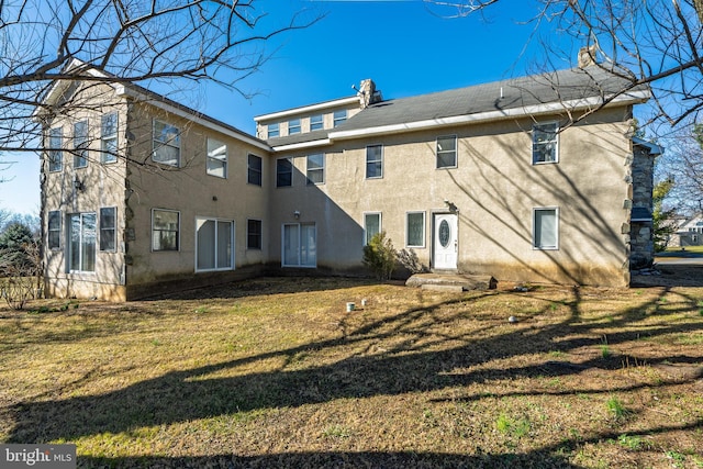 rear view of property with stucco siding and a yard