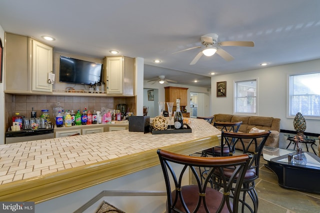 interior space featuring a kitchen bar, recessed lighting, a ceiling fan, and tasteful backsplash