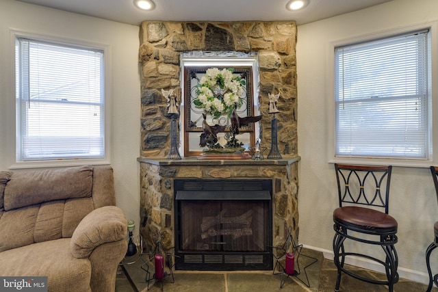 living area with recessed lighting, baseboards, and a stone fireplace