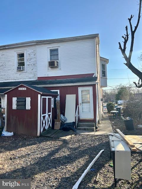 back of property featuring a storage unit, cooling unit, an outdoor structure, and entry steps