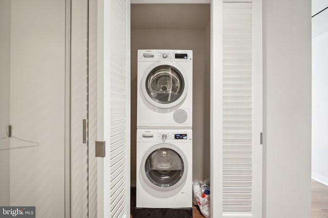 laundry room featuring stacked washer / dryer, laundry area, and wood finished floors