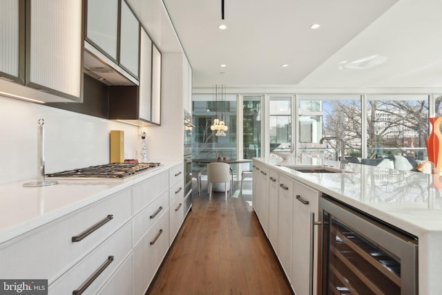 kitchen with dark wood-type flooring, beverage cooler, white cabinets, stainless steel appliances, and a sink