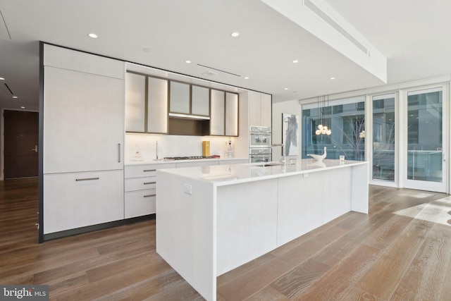 kitchen with wood finished floors, recessed lighting, gas stovetop, light countertops, and modern cabinets