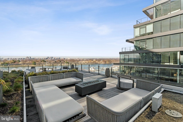 deck with an outdoor living space with a fire pit and a water view