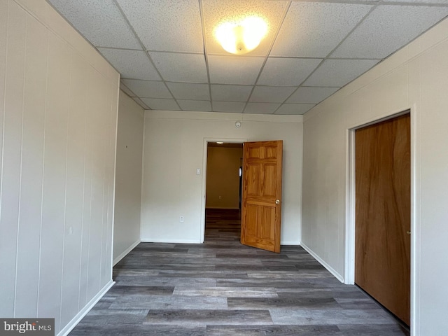 spare room featuring baseboards, a paneled ceiling, and wood finished floors