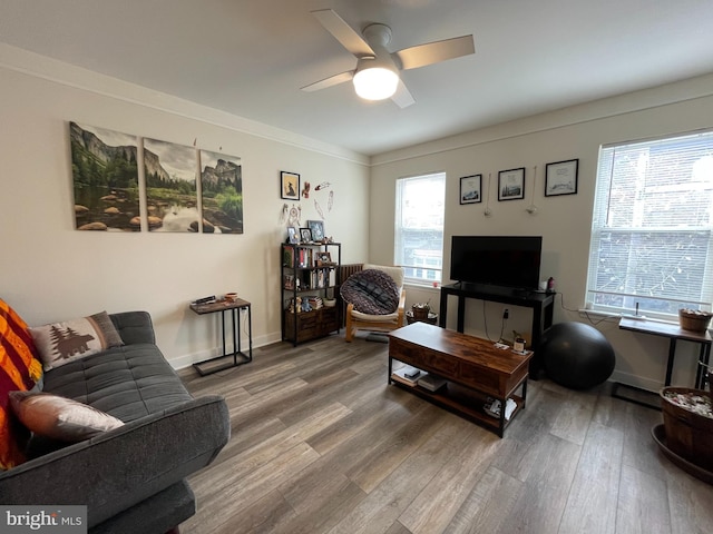 living area with baseboards, wood finished floors, and a ceiling fan