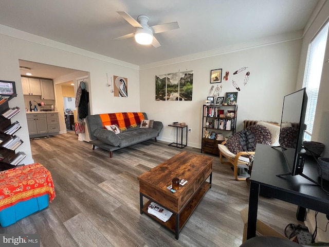 living room featuring ornamental molding, baseboards, a ceiling fan, and wood finished floors