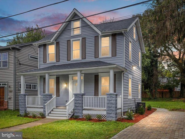 traditional style home featuring a porch, a front lawn, and a shingled roof