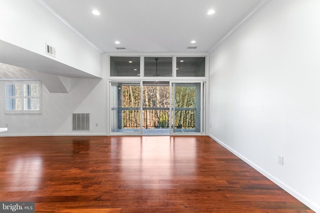 unfurnished living room featuring visible vents, baseboards, wood finished floors, and crown molding