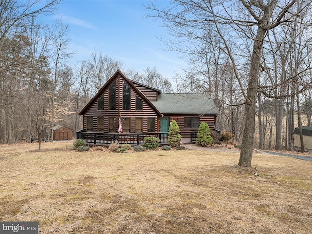 view of front facade with log siding, a shingled roof, and a front yard