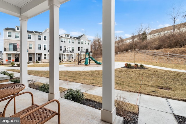 view of patio / terrace with a playground, fence, and a residential view