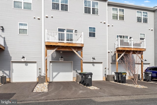 back of house with cooling unit, an attached garage, and driveway