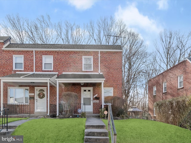 multi unit property featuring brick siding, a porch, a front lawn, and a shingled roof