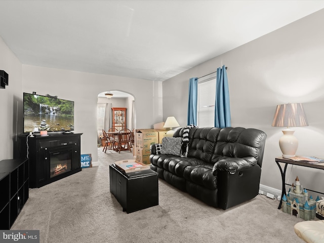 carpeted living area with arched walkways and baseboards