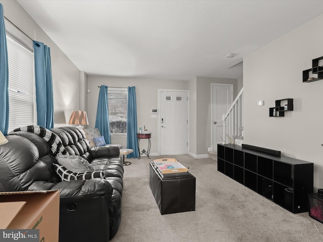 living area with baseboards, light colored carpet, and stairs