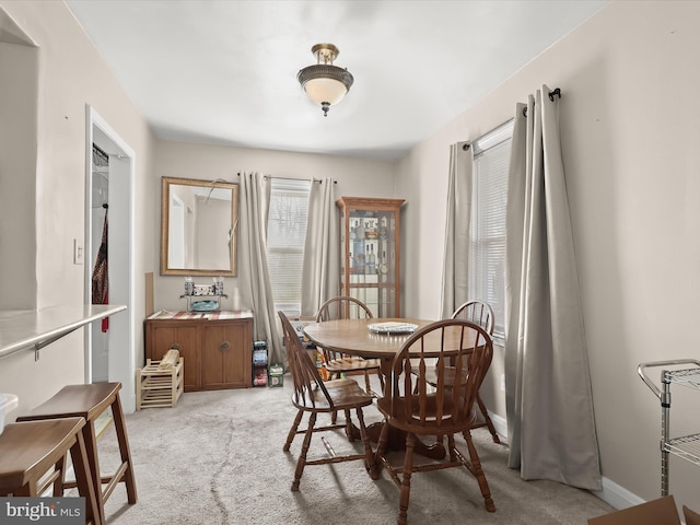 dining space featuring light colored carpet and baseboards