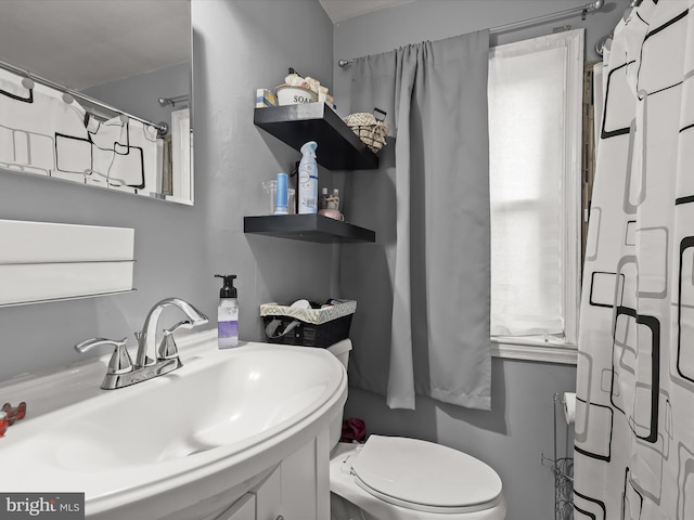 bathroom featuring curtained shower, toilet, and vanity