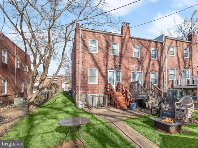 back of property featuring brick siding, a fire pit, and a chimney