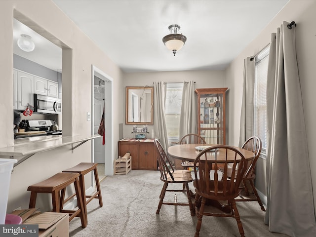 dining space featuring baseboards and light carpet