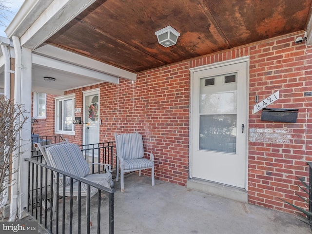 view of exterior entry with covered porch and brick siding